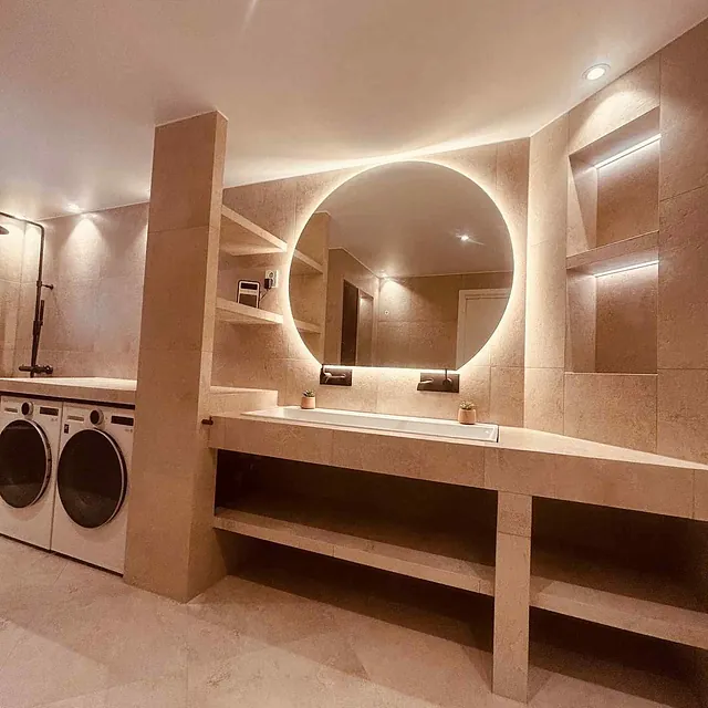 Moderne bad med beige fliser og rundt speil